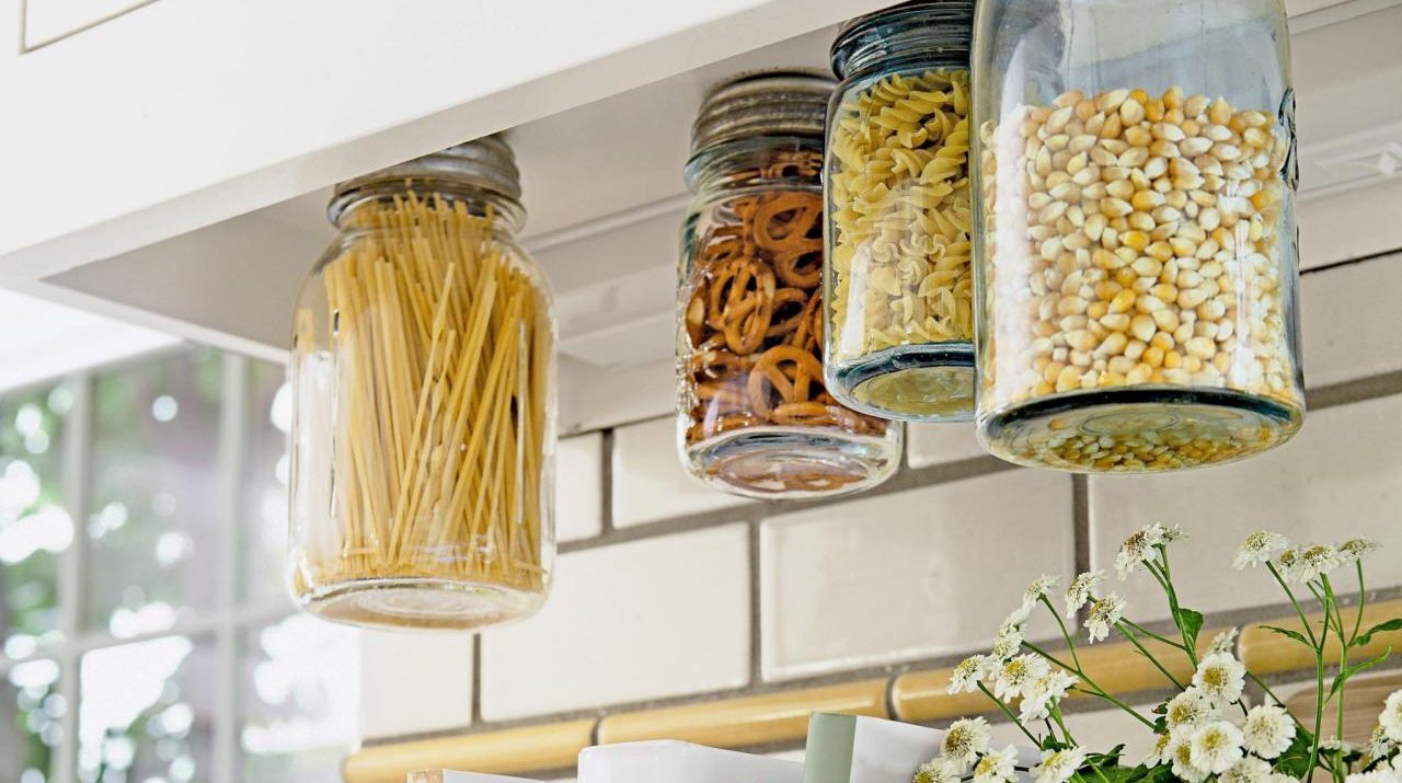 Mason jars screwed into the underside of a cabinet is a creative kitchen storage hack.