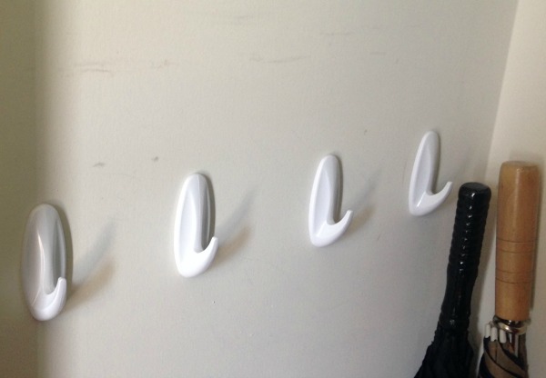 wall-mounted white coat hooks as a bedroom closet storage hack