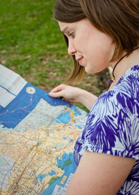 a woman wearing a white shirt with purple flowers is outside holding a map