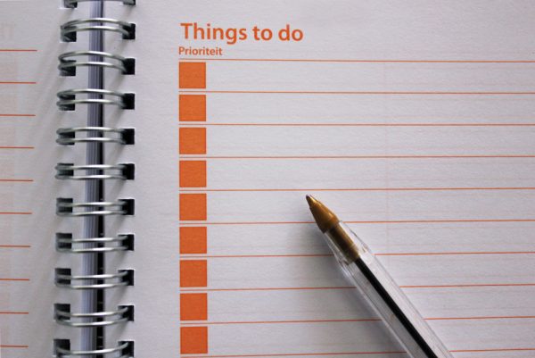 a pen on the inside of a things to do notebook is waiting for you to write your moving checklist