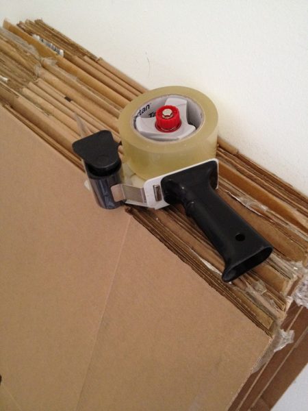 packing tape dispenser laying on folded moving and storage boxes