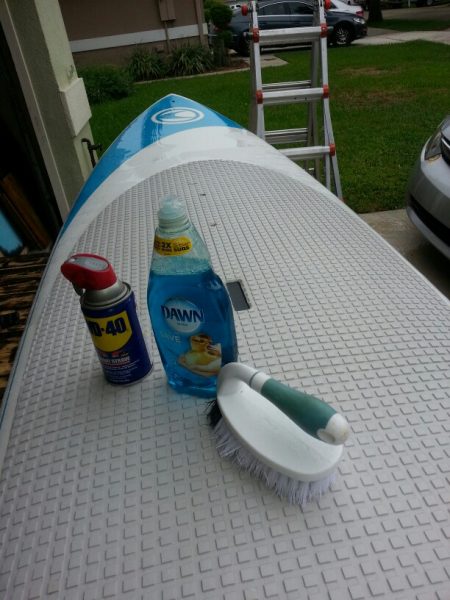 A can of WD40, surfboard, bottle of Dawn dish soap, and a brush