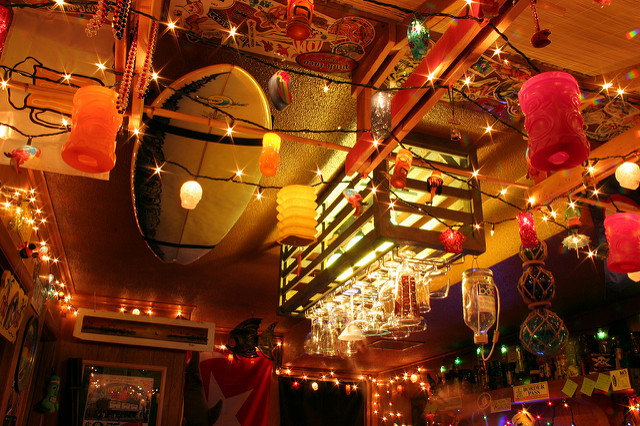 A surfboard ceiling rack is storing a surfboard in a tiki bar