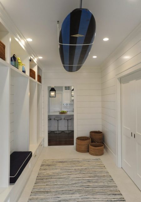 A white DIY surfboard ceiling rack is storing a black and blue-striped surfboard