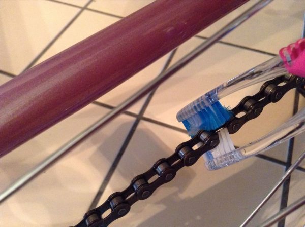 A DIY bike chain brush made by duct taping 2 toothbrushes together