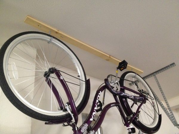 A beach cruiser hanging upside down on hooks in a garage