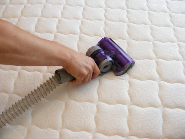 how to clean a mattress: vacuum it, spray upholstery cleaner on it, and let it air dry