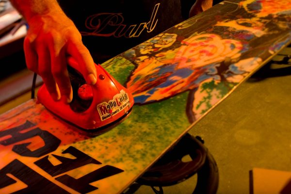 waxing a snowboard with a waxing iron