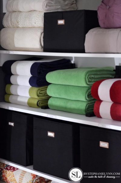 organized linen closet shelves with storage cubes with lids and folded towels