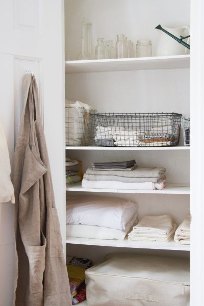 decluttered linen closet with fabric bags, storage crates, and folded bed sheets and bath towels