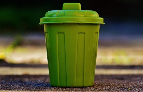 green trash can on a sidewalk