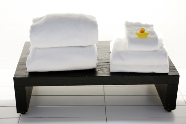 stacked towels and a rubber ducky on a bathroom stand