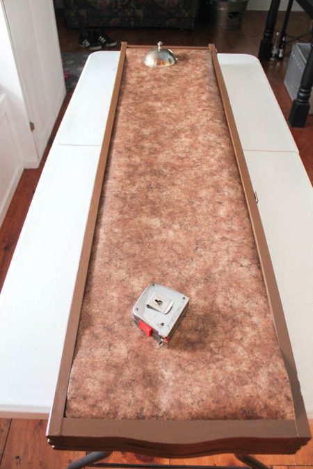 room divider panel with mottled brown wallpaper and a tape measure on top