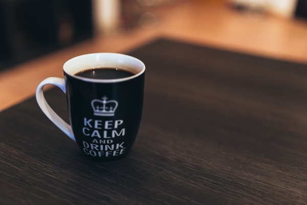 hygge coffee mug that reads "keep calm and drink coffee" on a coffee table