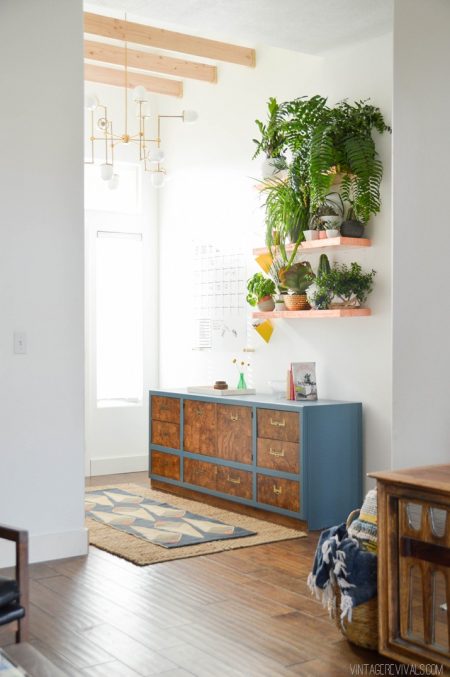 entryway makeover consisting of copper floating shelves, potted plants, and a console with drawers