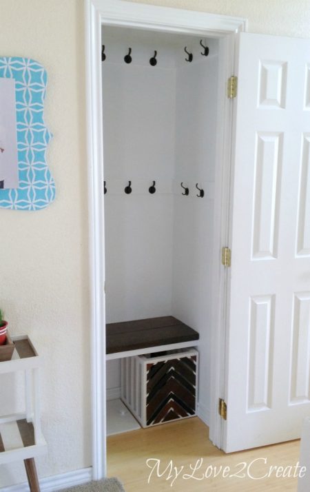 hall closet makeover with wall hooks, a bench, and a storage crate