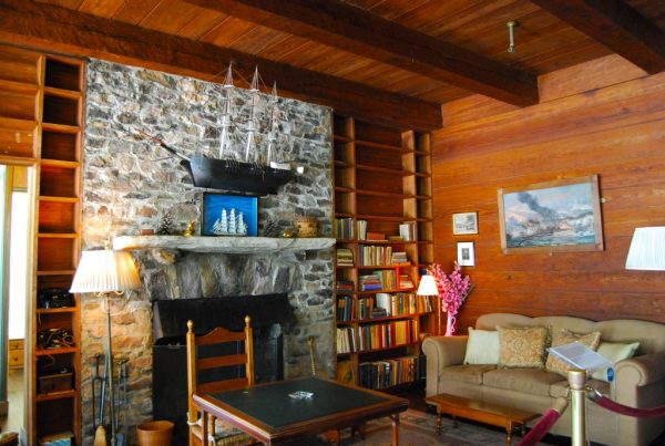 the living room in fdr's little white house in warm springs, ga has above door shelves, wall shelves, and a fireplace