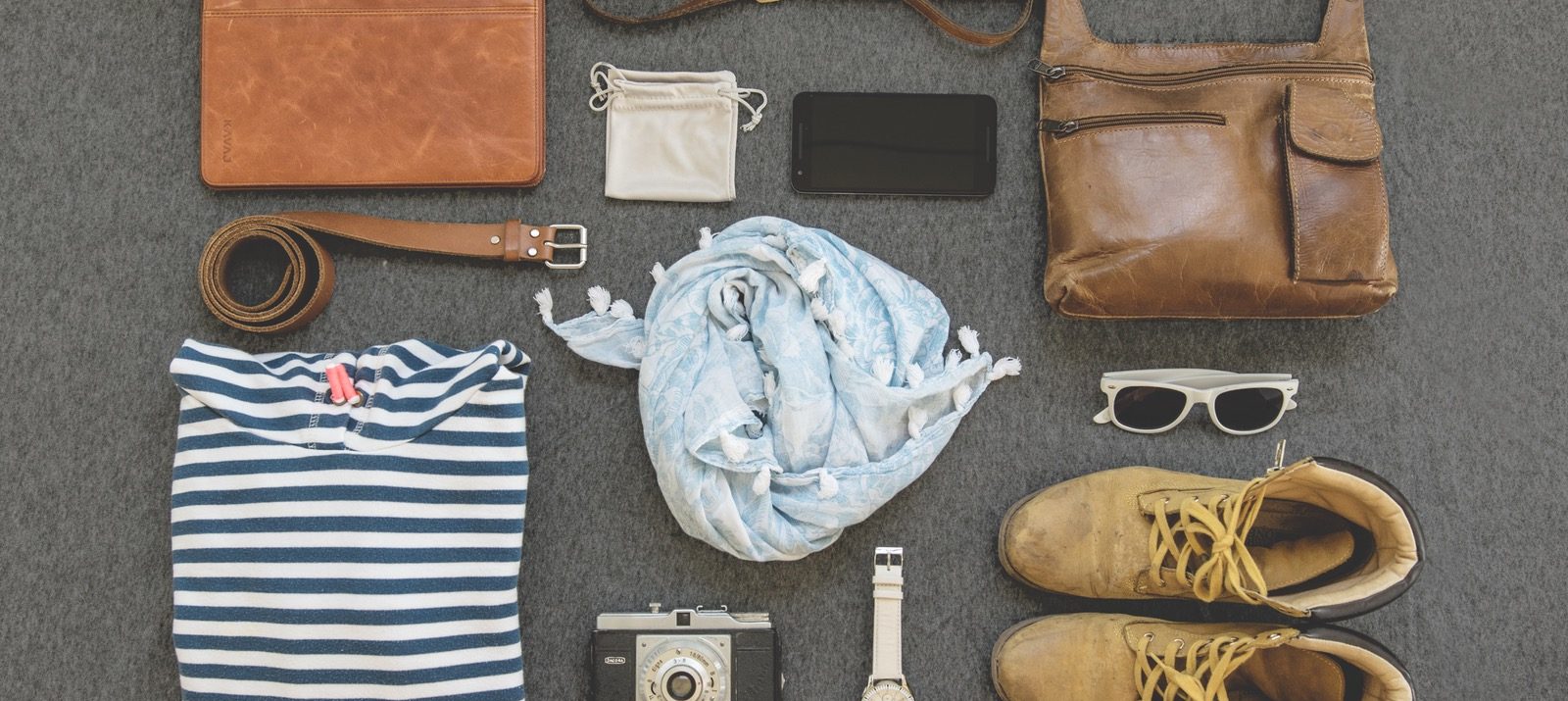 clothes, boots, cell phone, belt, sunglasses, camera, watch, bag, binder, and pouch organized neatly