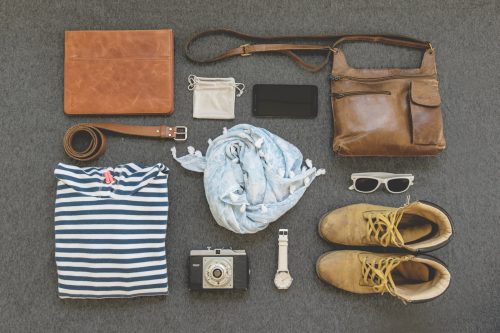 clothes, boots, cell phone, belt, sunglasses, camera, watch, bag, binder, and pouch organized neatly