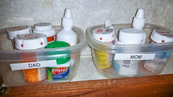 "dad" and "mom" labeled medication holders in a medicine cabinet