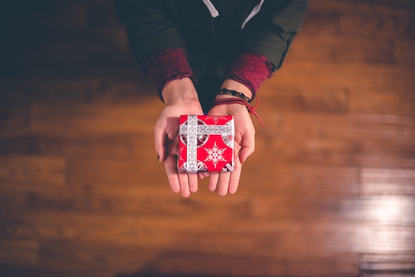 hands giving a holiday gift to someone