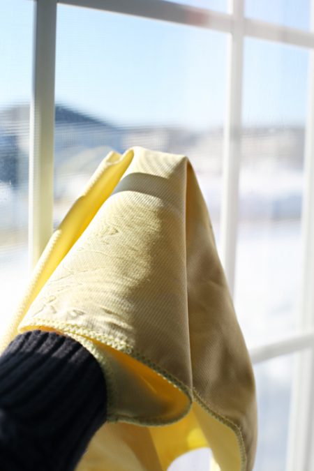 cleaning a window with a yellow glass polishing rag