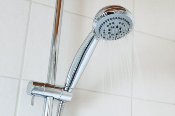 water coming out of a clean shower head in a bathroom