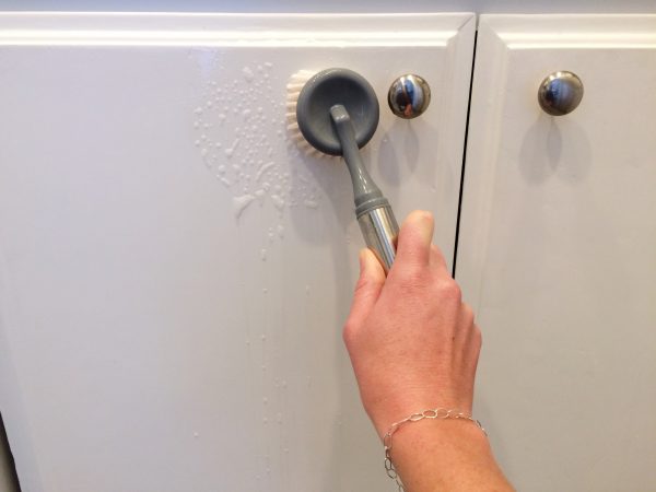 paige smith cleaning kitchen cabinets with dish soap and a dish brush