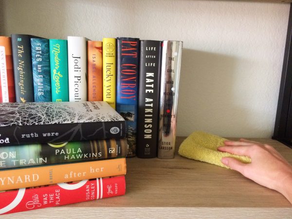 paige smith wiping a wooden bookshelf with a yellow magnetic cloth
