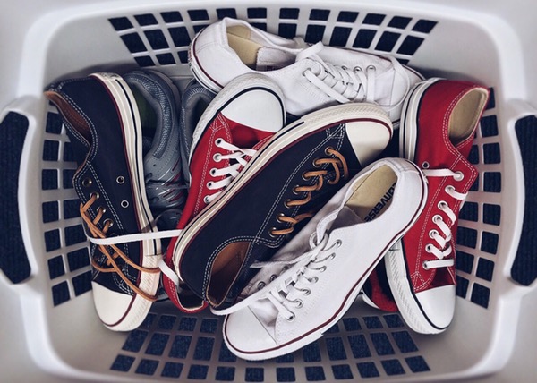 multiple pairs of white, red, and black converse chuck taylors in a laundry basket