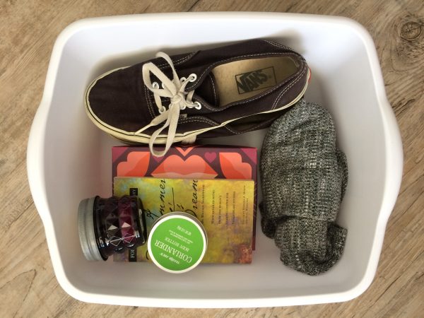 white reuse bin by paige smith storing socks, roiander body butter, a candle, books, and a pair of vans shoes