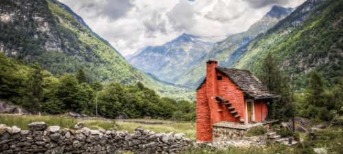 tiny red house on a sunny day with mountains in the background