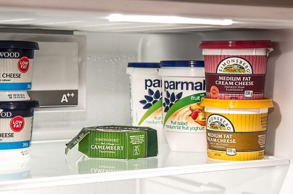 cheese, cream cheese, and yogurt containers on a fridge shelf