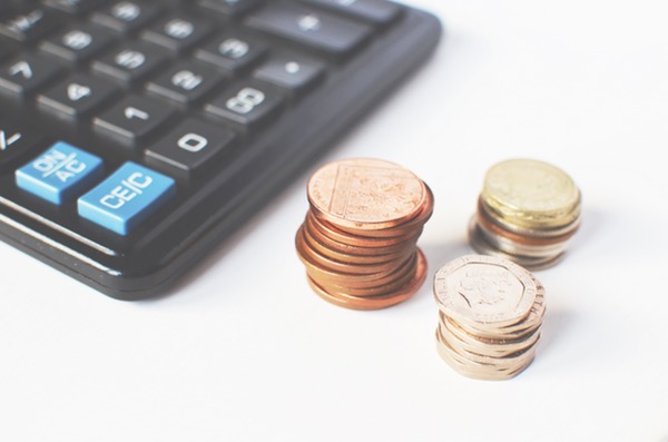 calculator next to 3 short stacks of different coins