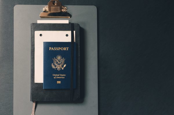 us passport atop a small sheet of paper, a small notebook, and a clipboard