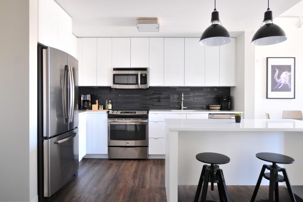 modern apartment kitchen with a fridge, freezer, stove, oven, microwave, 2 coffee makers, a kitchen island, and 2 stools