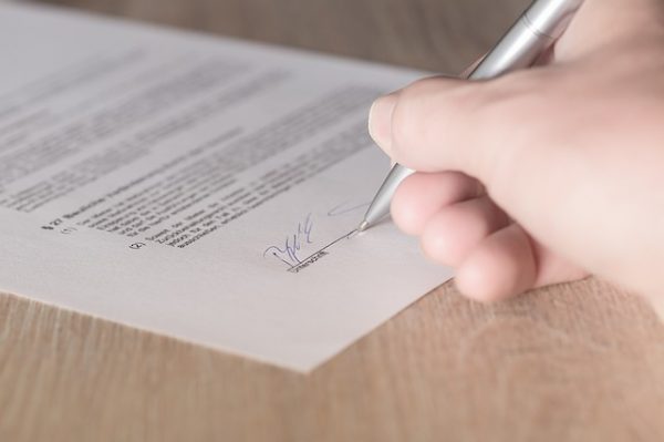 hand signing apartment lease with a pen