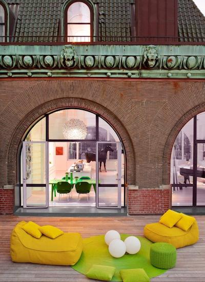 ghislaine vinas' fun outdoor decor: 2 mustard outdoor seats, a green circle rug with 3 giant ping pong balls on top, and a green ottoman 