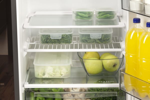 fruits and vegetables stored in plastic food containers with lids in a fridge