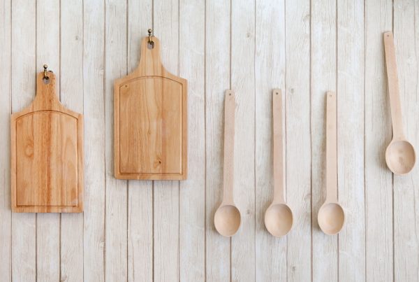 2 wooden cutting boards and 4 cooking spoons hanging on wall-mounted hooks