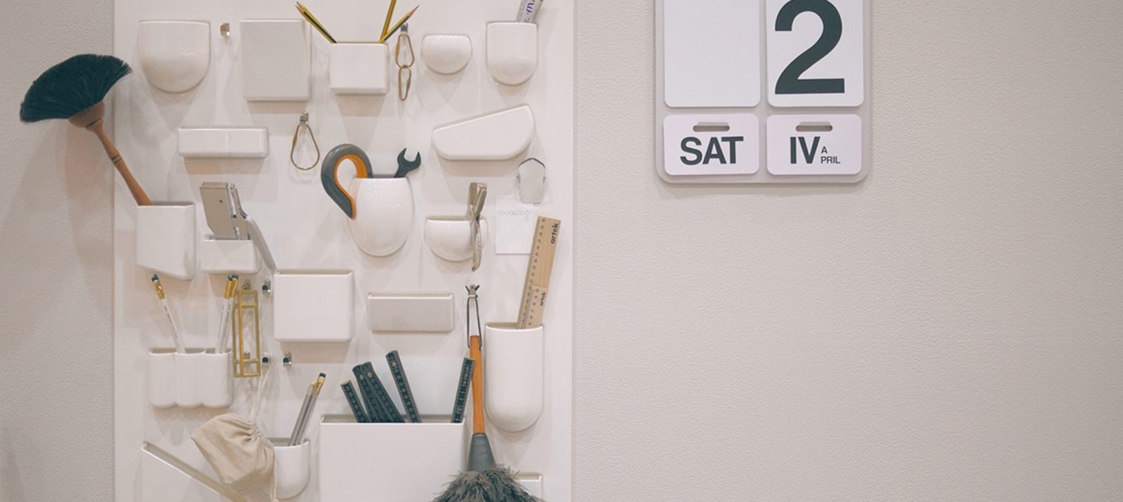white wall organizers and a wall-mounted calendar with large numbers and letters