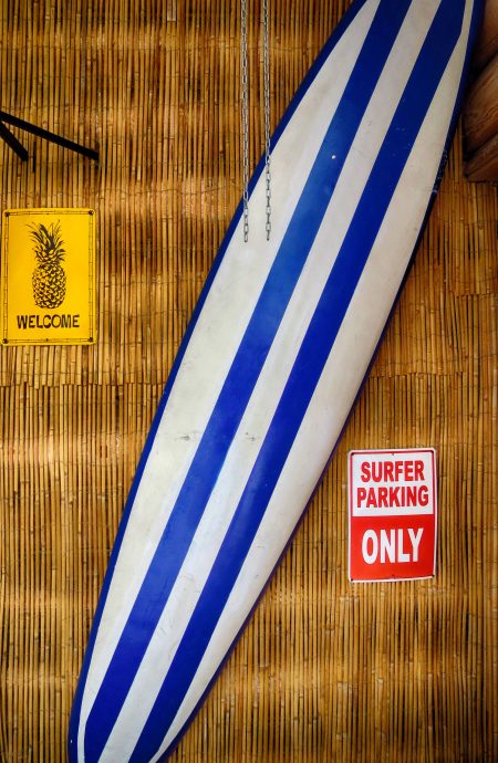 blue and white surfboard against a bamboo wall