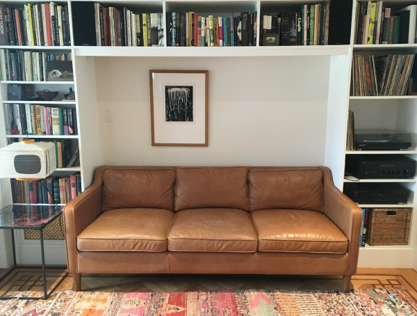 brown leather sofa surrounded on all sides by a bookcase
