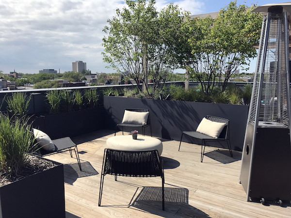 brianne bishop's luxe on chicago rooftop project scene 3: a circular coffee table surrounded by 4 outdoor chairs with pillows