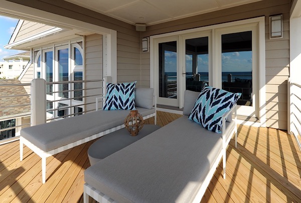 2 outdoor lounge chairs with cushions, patterned throw pillows, and an oval-shaped coffee table - designed by paola mcdonald