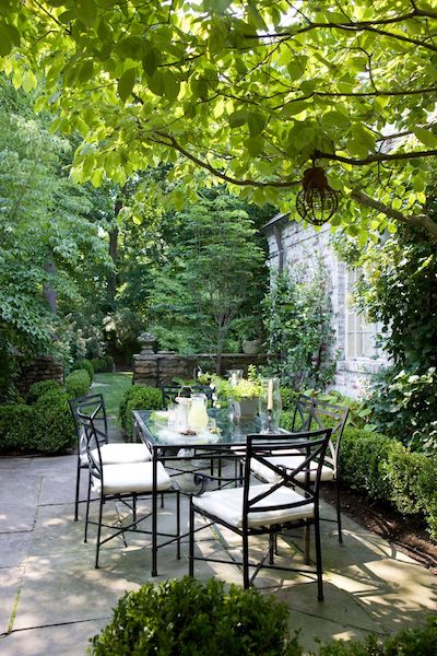 outdoor dining table and chairs with cushions on a backyard patio designed by kelley proxmire
