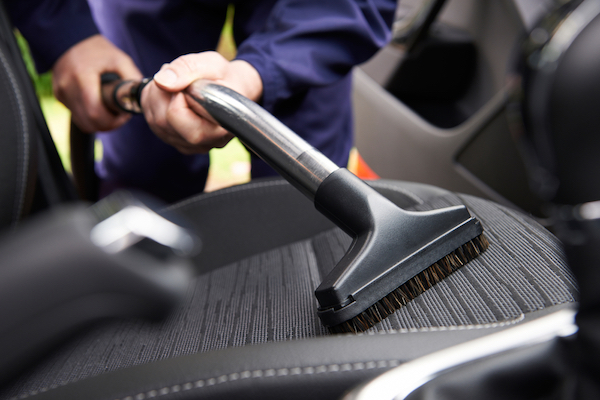 A person vacuuming his car seat.