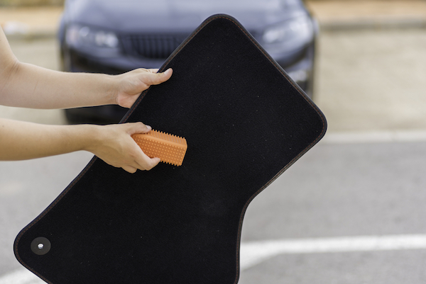 A woman is cleaning the carpet of her car.