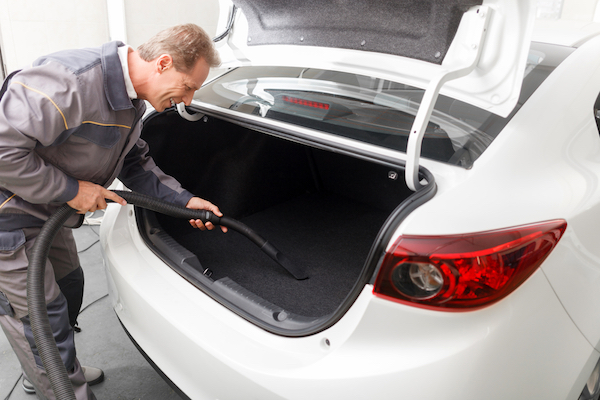 A man vacuums the trunk of his car.