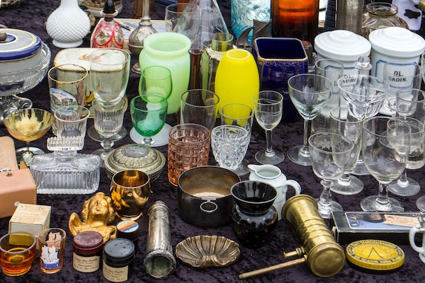 A table full of cups, bowls, and other miscellanea at a flea market.